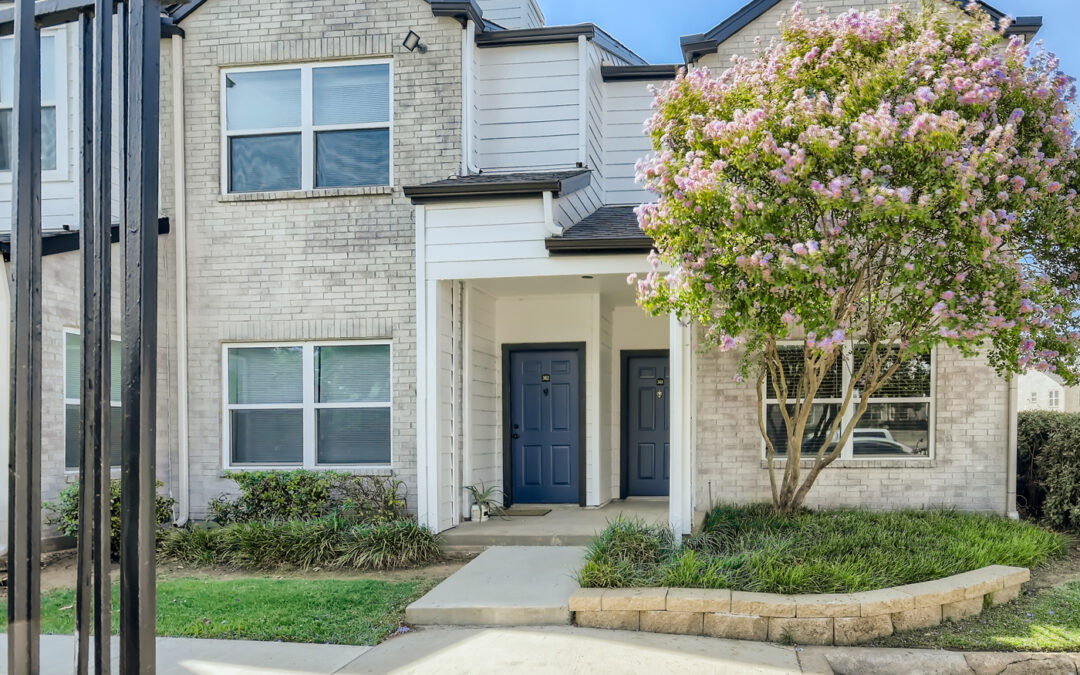 White brick two story building with flowering tree in front