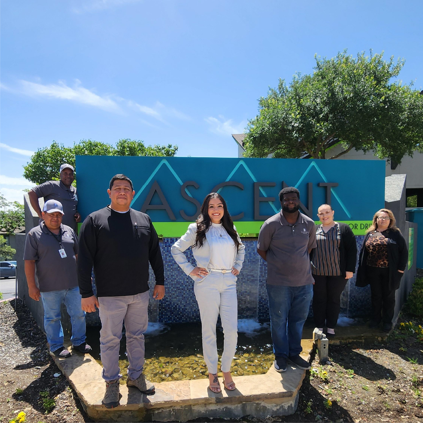 Leasing Team standing in front of community monument sign