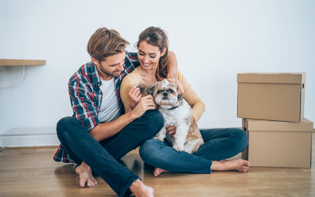 Young couple with dog sitting on the floor at their new home.